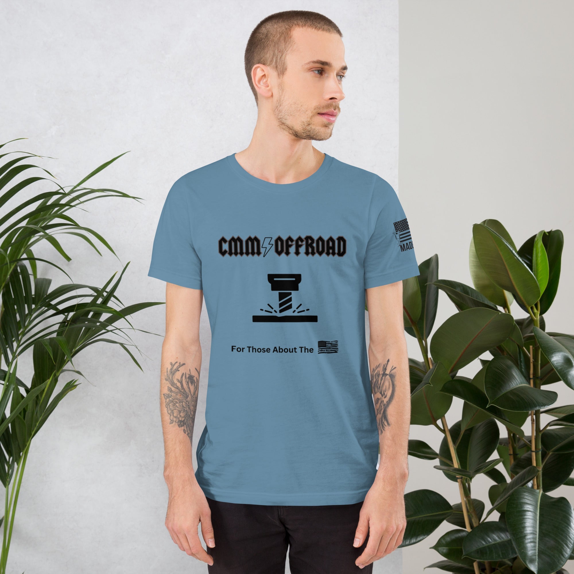 Man wearing steel blue unisex offroad graphic t-shirt indoors with plants nearby
