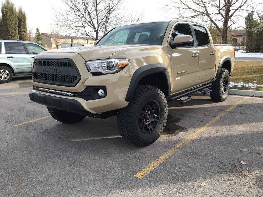 Lifted Toyota Tacoma truck with off-road tires and side steps in a parking lot