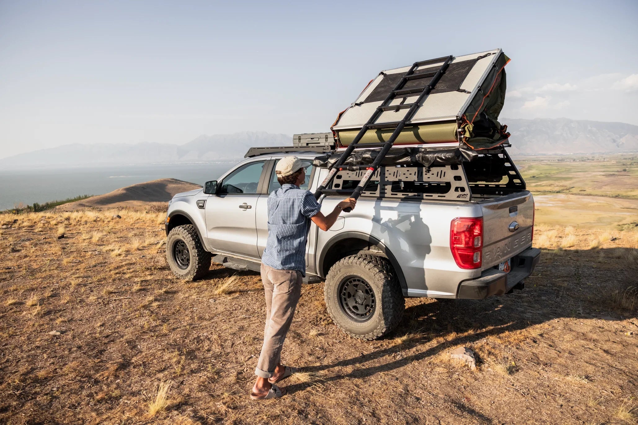 Overlanding truck with rooftop tent setup on a scenic hilltop for expedition camping adventure
