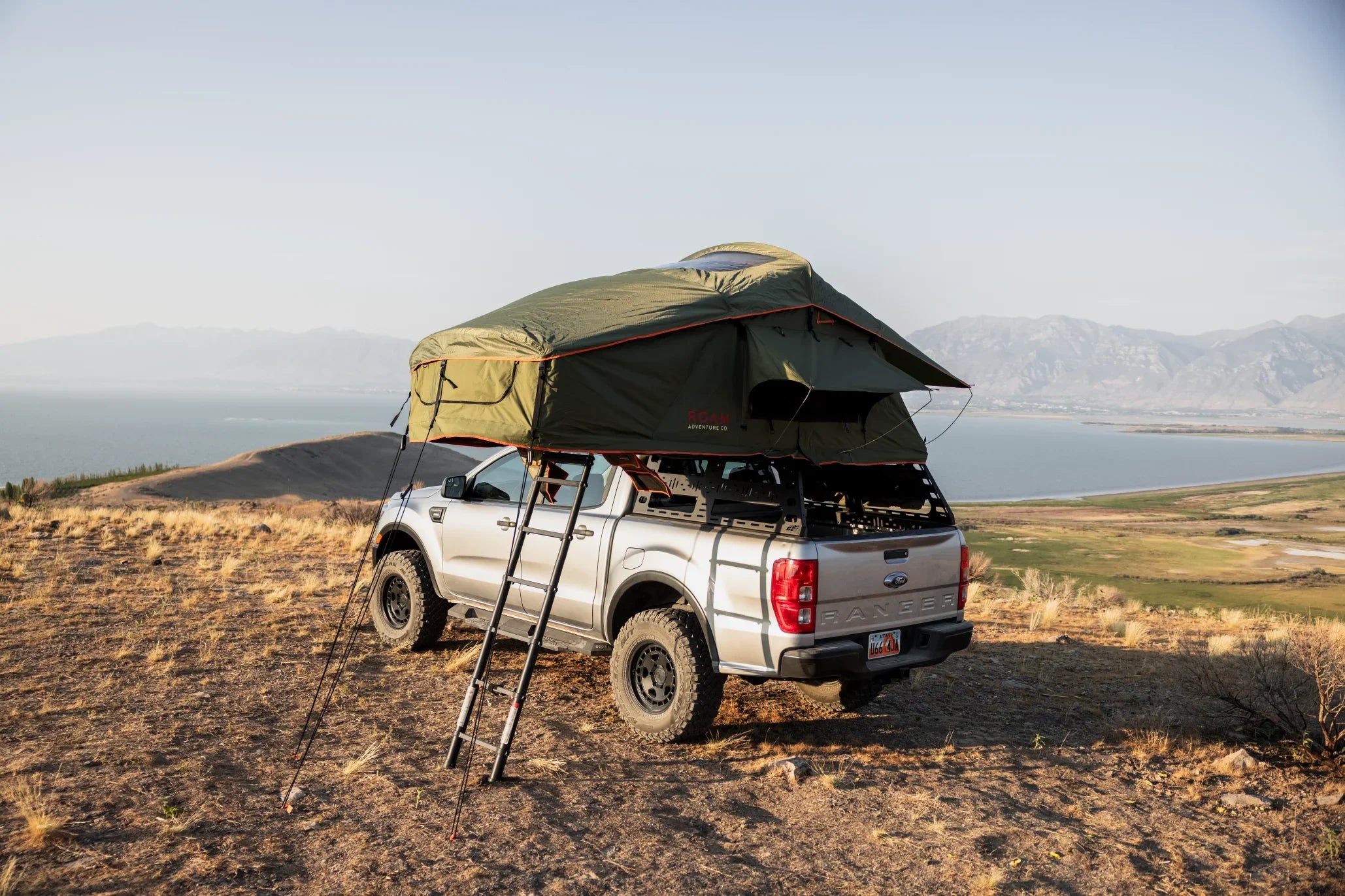 Ford Ranger with roof top tent camping gear parked on hilltop overlooking lake and mountains