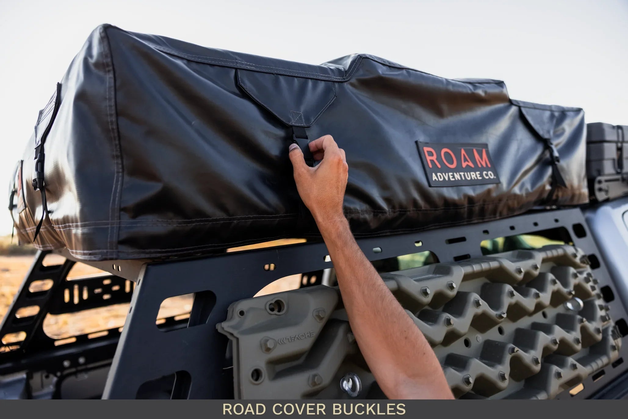 Hand securing buckle on ROAM roof top storage bag mounted on overlanding vehicle rack