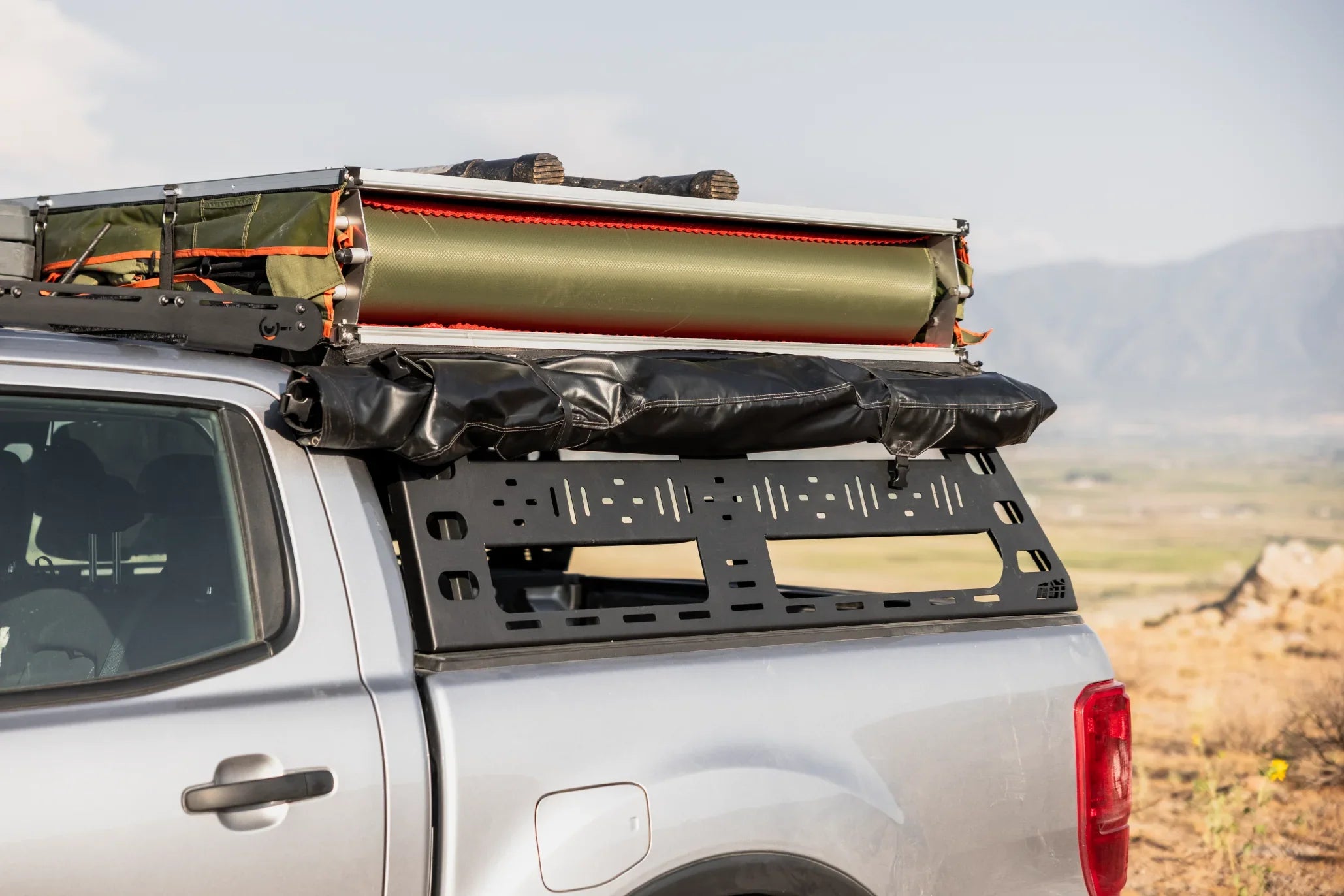 Overlanding truck with modular bed rack and rooftop tent setup, ideal for expedition camping