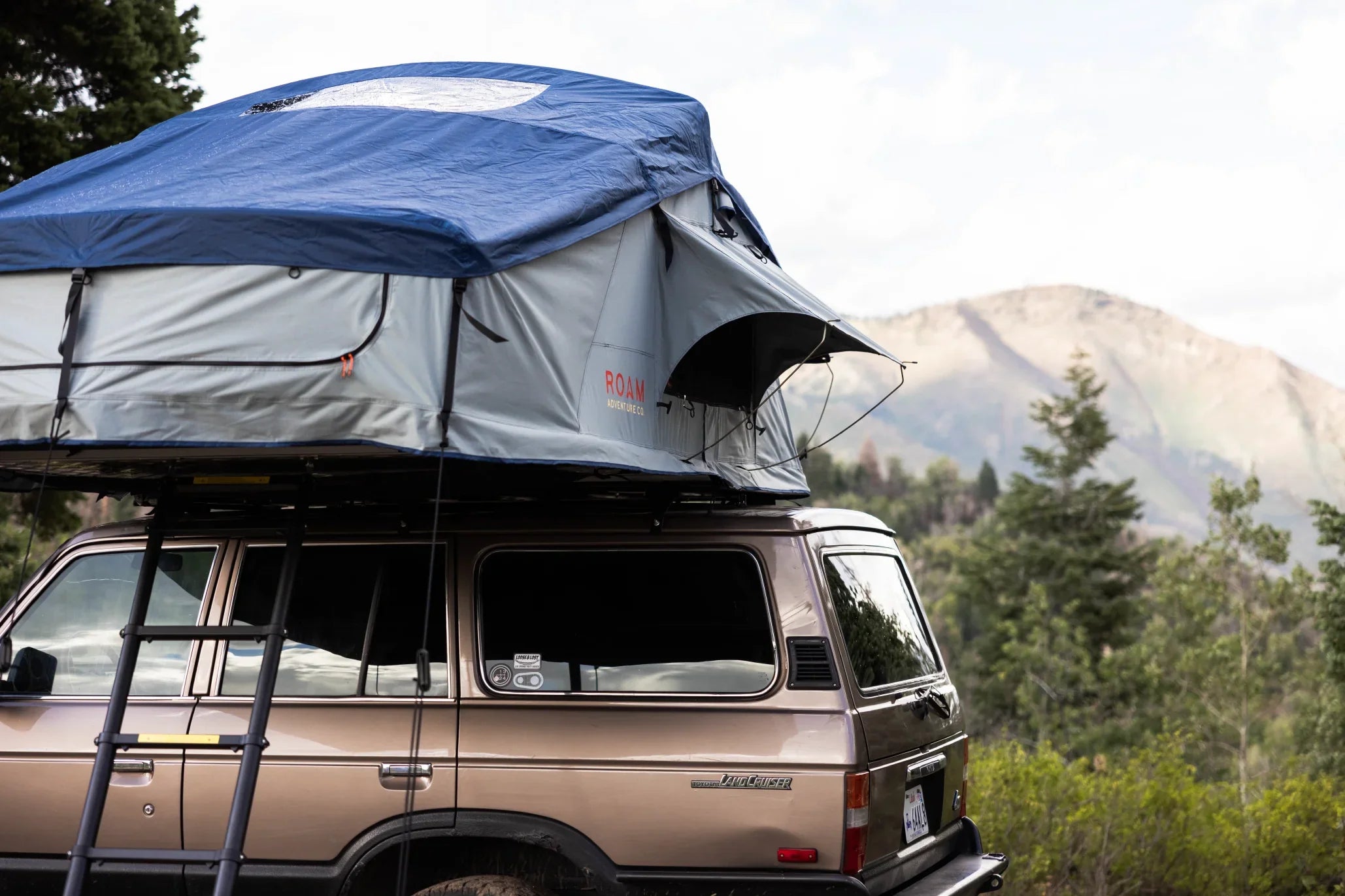 SUV with rooftop tent for overlanding and camping in mountain wilderness