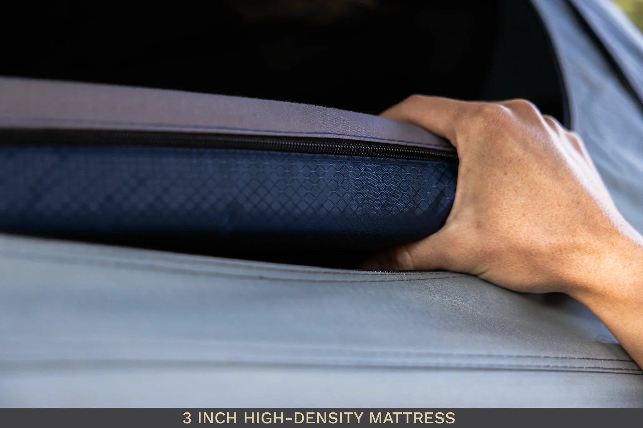 Hand pressing a 3 inch high-density camping mattress with textured cover