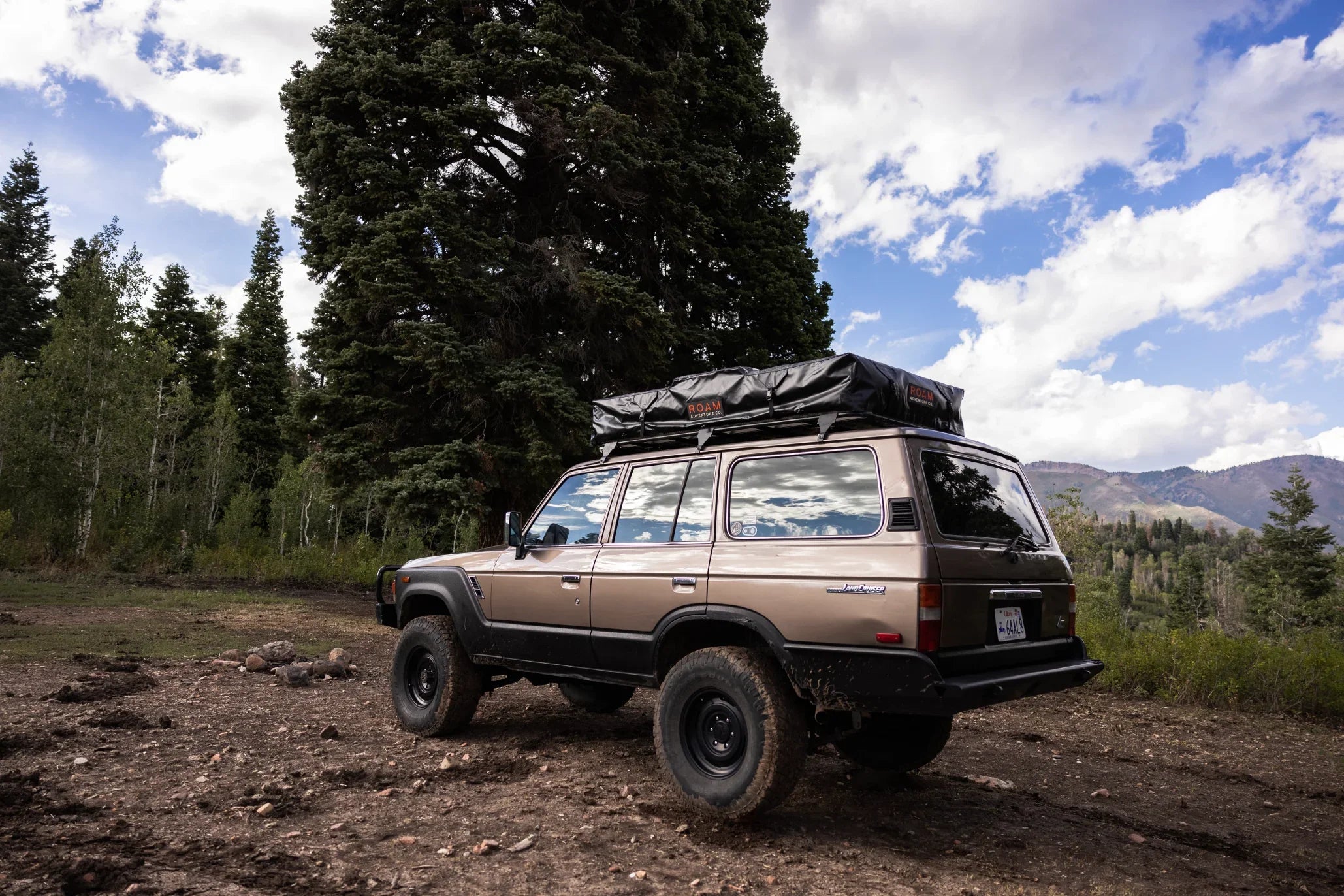 Classic SUV with rooftop tent parked in forest, ideal for overlanding and camping