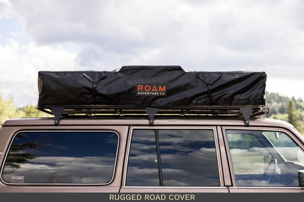 Overland vehicle with black roof top tent and rugged road cover for camping