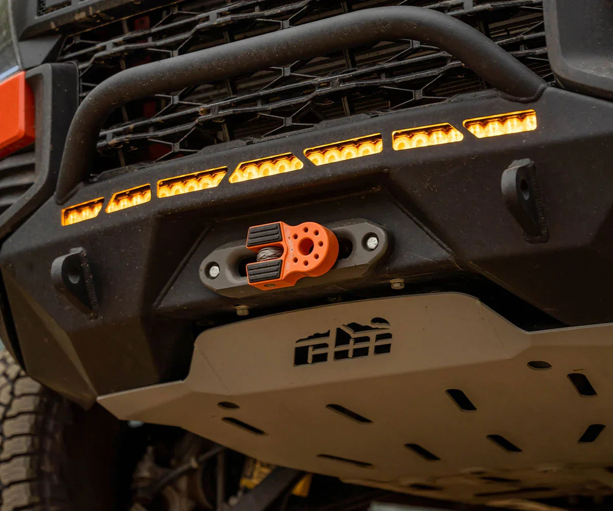 Off-road vehicle front bumper with orange recovery winch, skid plate, and amber LED lights